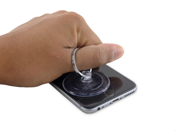 آیفون تعمیری را روی میز کارتان قرار دهید. با انگشت شصت خود گیره ساکشن کاپ را گرفته و انتهای دستتان را روی صفحه نمایش گوشی تکیه دهید تا از جابجا شدن آن جلوگیری به عمل آید.
