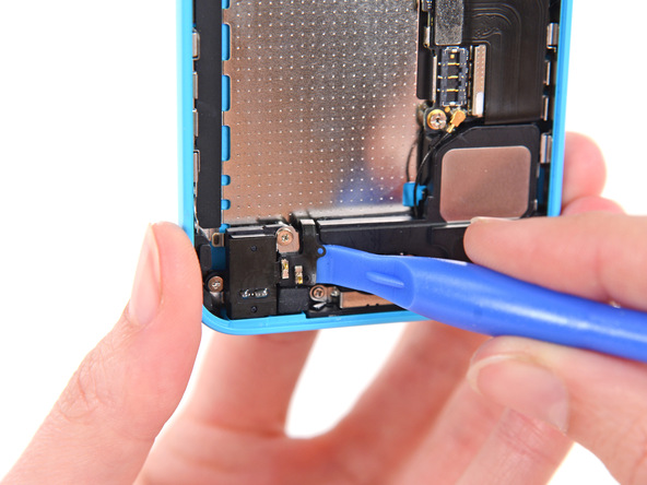 به آرامی با نوک قاب باز کن پلاستیکی کانتکت فنری دکمه هوم آیفون 5C را از روی محفظه اسپیکر گوشی آزاد کنید.