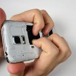 گلکسی اس 5 مینی تعمیری را مثل عکس اول در دستتان بگیرید. دقت کنید که انگشت اشاره و میانی دو دست شما باید در جایی از بدنه گوشی قرار بگیرند که باتری روی آن سوار می‌شود.