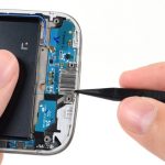 روی سوکت شارژ Galaxy S4 تعمیری یک براکت خاص و فنری نصب است. نوک اسپاتول را زیر لبه سمت راست این براکت فرو برده و آن را به سمت بالا هول دهید تا از روی سوکت شارژ گوشی بلند شود.