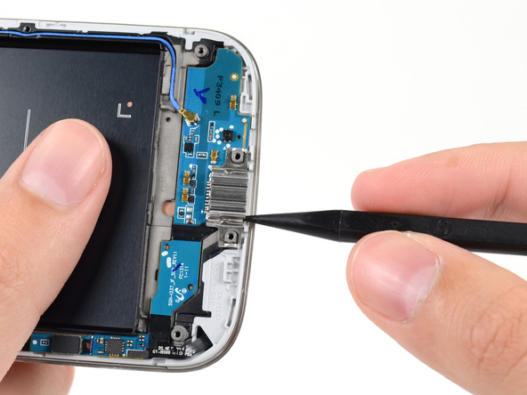 روی سوکت شارژ Galaxy S4 تعمیری یک براکت خاص و فنری نصب است. نوک اسپاتول را زیر لبه سمت راست این براکت فرو برده و آن را به سمت بالا هول دهید تا از روی سوکت شارژ گوشی بلند شود.