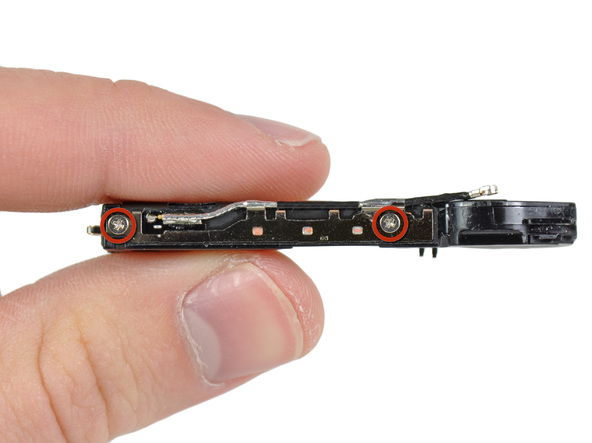 دو پیچی که در عکس با رنگ قرمز مشخص شده‌اند را از روی محفظه اسپیکر آیفون 4 تعمیری باز کنید. این دو پیچ سیم آنتن زیرین آیفون 4 را روی محفظه اسپیکر گوشی متصل می‌کنند.