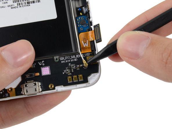 کانکتور یکی از دو سمت سیم آنتن گلکسی نوت تعمیری همچنان روی برد USB گوشی نصب است. این بخش از کانکتور سیم آنتن گوشی را آزاد کنید.