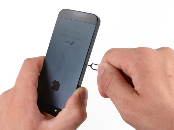 سوزن باز کننده سیم کارت آیفون 5 را در داخلی مجرای روی لبه قاب گوشی فرو کنید.