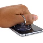 آیفون 6S Plus تعمیری را روی میز کارتان قرار دهید. دست خود را روی نمایشگر گوشی قرار داده و فشار دهید تا از جابجا شدن آیفون جلوگیری شود.