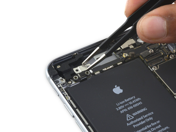براکت کابل کنترل صدای آیفون 6S Plus تعمیری را با پنس از روی پنل پشت گوشی جدا کنید.
