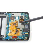 نوک اسپاتول را زیر کانکتور لنز دوربین اصلی Nexus 5 تعمیری قرار دهید و خیلی آرام آن را به سمت بالا هدایت کنید تا کانکتور مذکور از روی مادربرد گوشی آزاد شود.