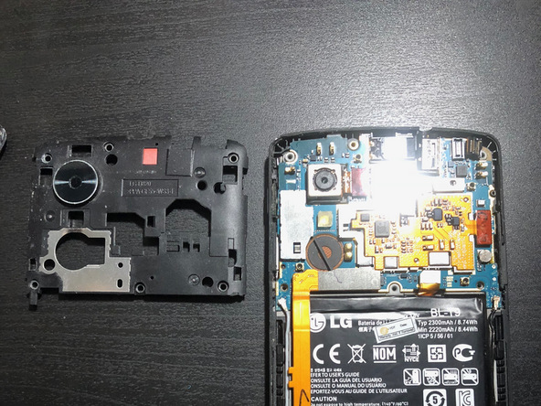 با اسپاتول یا قاب باز کن بخش فوقانی فریم محافظ برد را با دست گرفته و کاملا از روی مادربرد Nexus 5 تعمیری جدا نمایید.